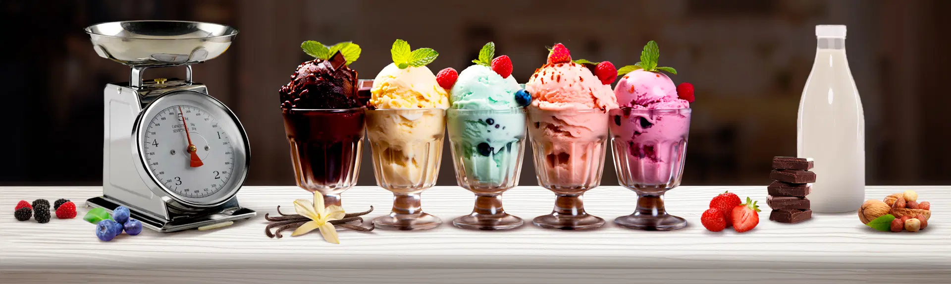 5 Copas servidas con helados de diferentes sabores, una balanza y un litro de leche como portada del artículo Fabricación de helado