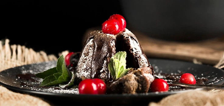 Volcán de chocolate servido con cerezas rojas