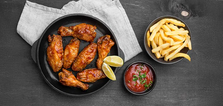 Alitas y papas fritas con catsup sobre una mesa