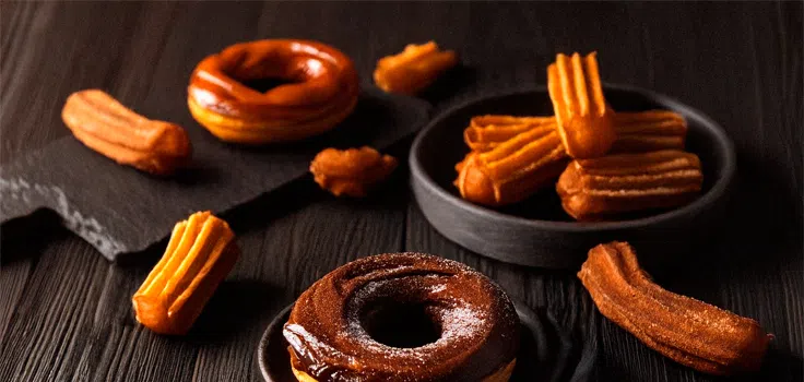 Donas glaseadas y churros sobre una mesa